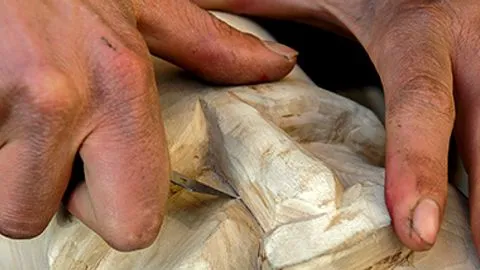 Mani al lavoro nell’intaglio di un oggetto in legno.